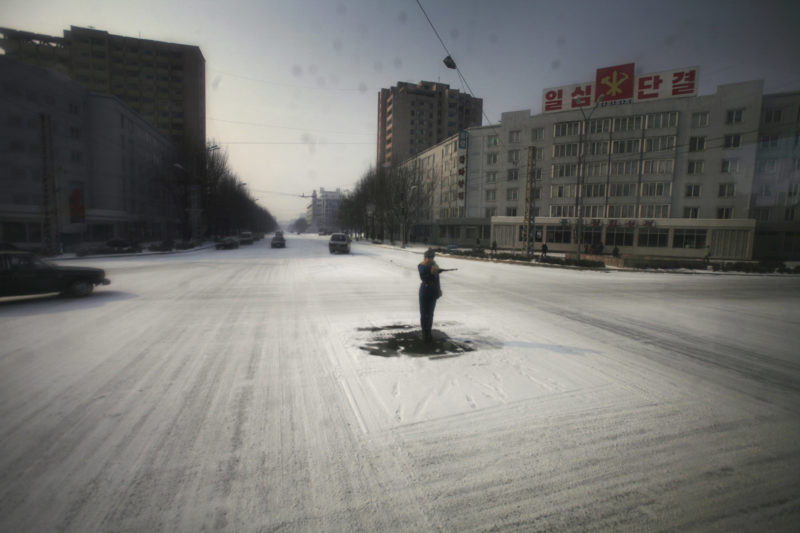 David Guttenfelder - A traffic guard goes through the motions in the capital of Pyongyang, where streets are almost empty of cars