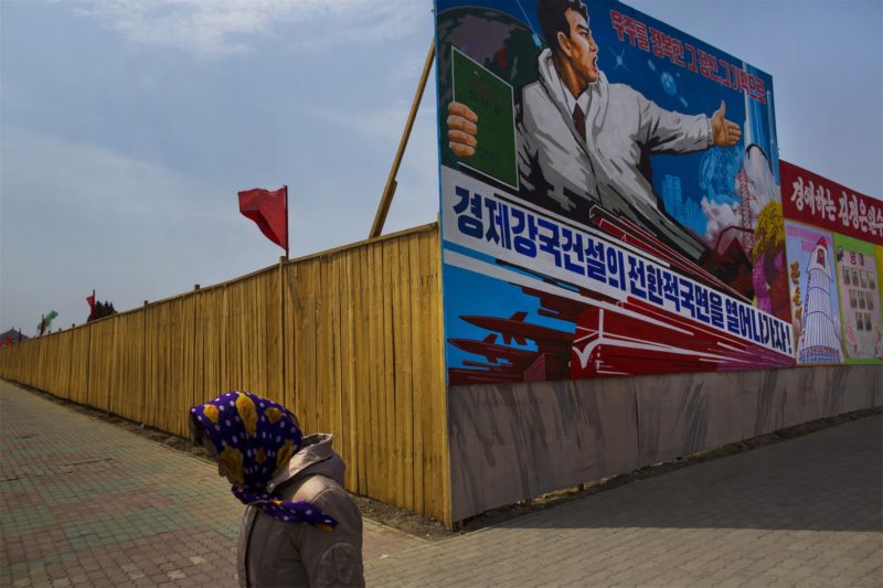 David Guttenfelder - A woman in Pyongyang walks past a billboard advertising North Korea’s missile prowess. The capital city is rife with stylized propaganda