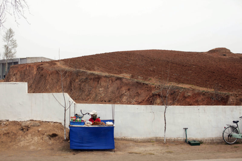 David Guttenfelder - In this April 21, 2011 photo, a woman sits at a small table selling snacks on the roadside along the West Sea Barrage near Nampho, North Korea