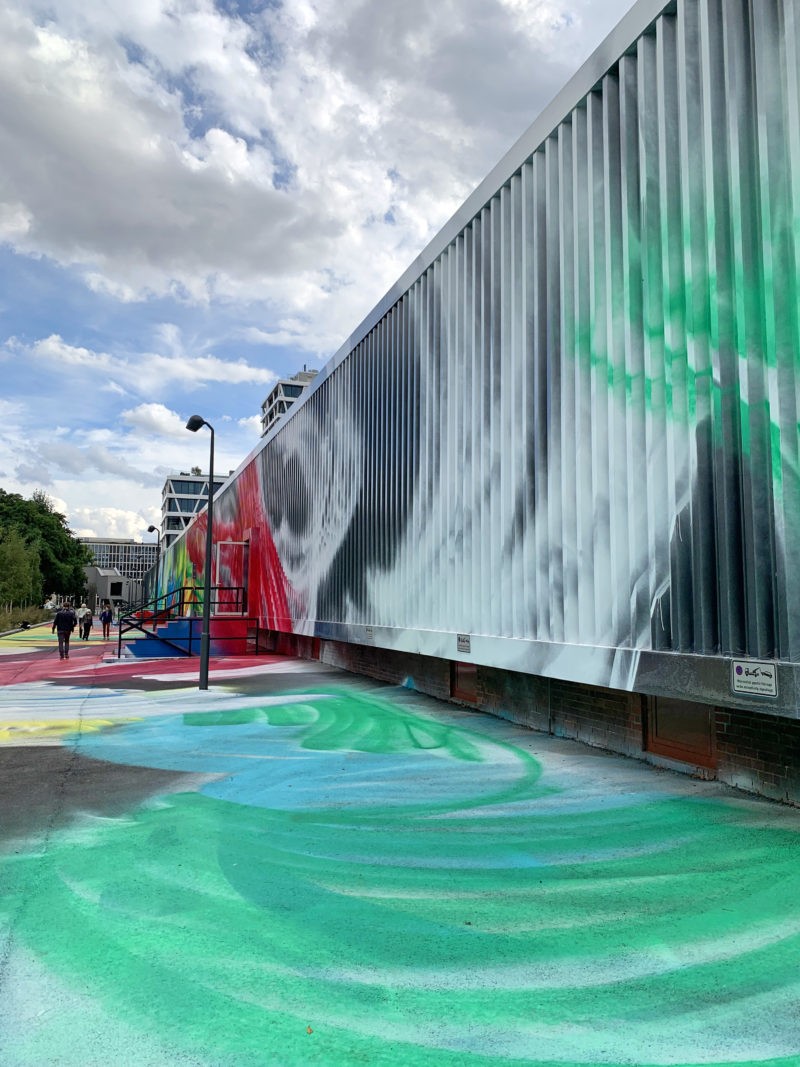 Katharina Grosse - It Wasn’t Us, 2020, acrylic on floor, polystyrene and bronze; paint on asphalt, concrete, brick and metal, 7 x 6,5 x 18,3 m, installation view, Hamburger Bahnhof, Berlin