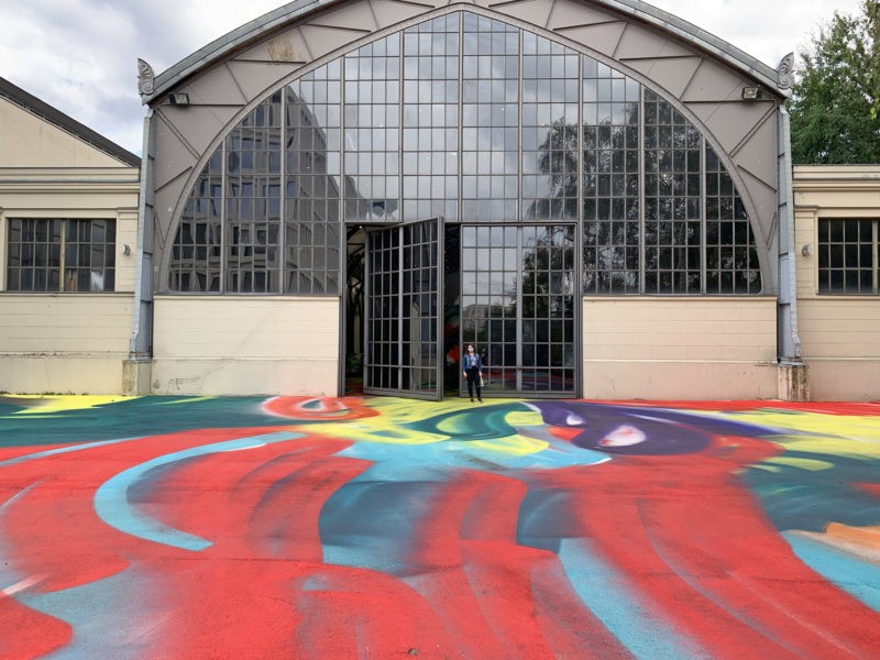 Katharina Grosse - It Wasn’t Us, 2020, acrylic on floor, polystyrene and bronze; paint on asphalt, concrete, brick and metal, 7 x 6,5 x 18,3 m, installation view, Hamburger Bahnhof, Berlin