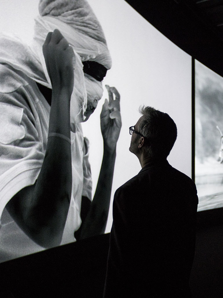 One visitor looking at Christie projection at Richard Mosse exhibition Barbican Centre