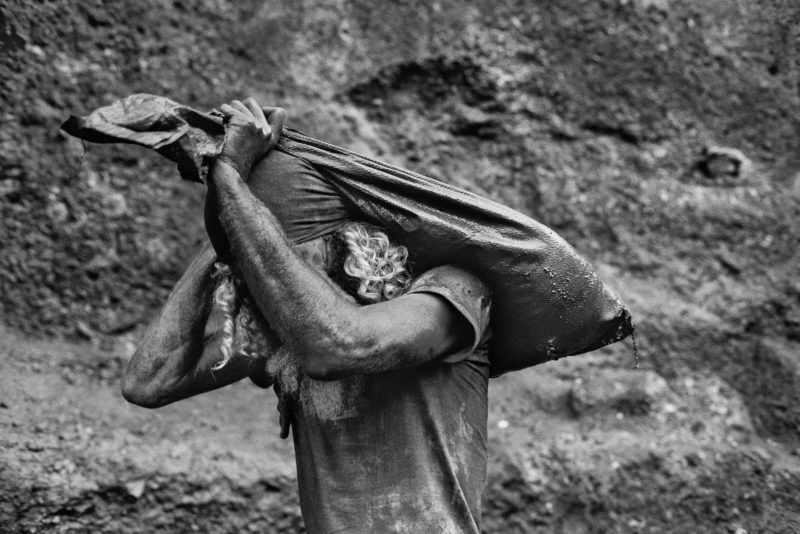 Sebastiao Salgado – Serra Pelada Gold Mine, Brazil, 1986, A worker carries a sack of dirt out of the mine