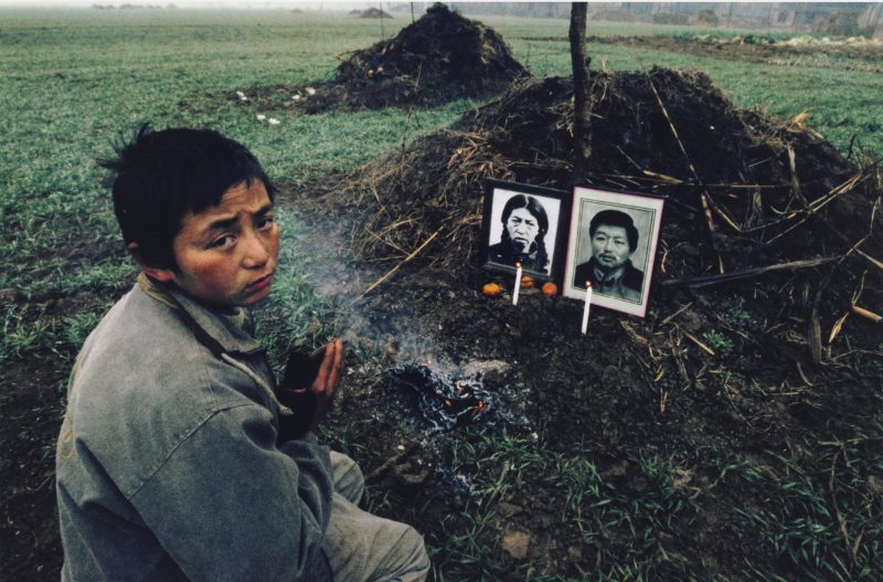 Lu Guang - Gao Rongsheng (13) at the grave of his parents.