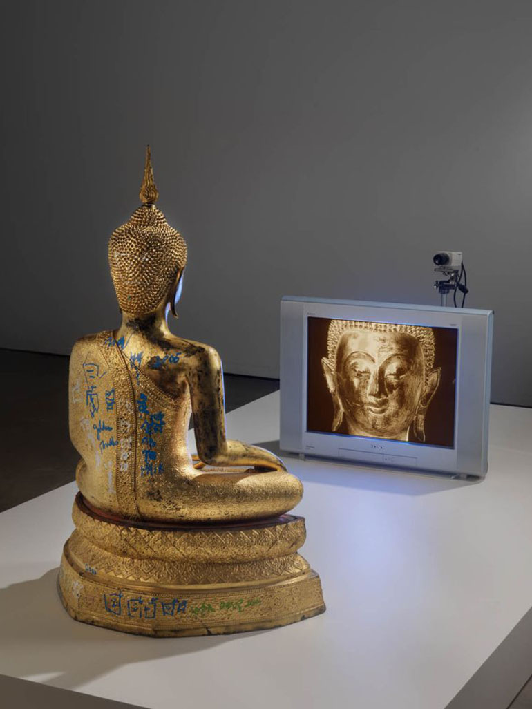 Nam-June-Paik-Golden-Buddha-2005-closed-circuit-video-color-with-television-and-wood-Buddha-with-permanent-oil-marker-additions-46-12-×-106-×-31-34-inches-118.1-×-269.2-×-80.6-cm