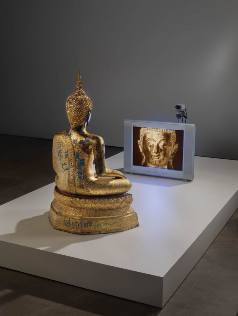 Nam June Paik - Golden Buddha, 2005, closed-circuit video (color) with television and wood Buddha with permanent oil marker additions, 46 1/2 × 106 × 31 3/4 inches (118.1 × 269.2 × 80.6 cm)