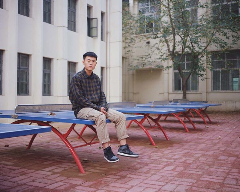 Shi Yangkun - Guo Tianlong, from Nanjie Village, sits on a pingpong table in Henan province, 2018