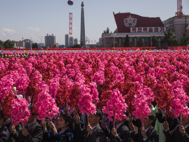 David Guttenfelder - North Korean civilians wave pink and red artificial flowers and chant "Kim Jong Un" on Kim Il Sung Square in Pyongyang during a mass military parade to mark its 70th anniversary as a nation