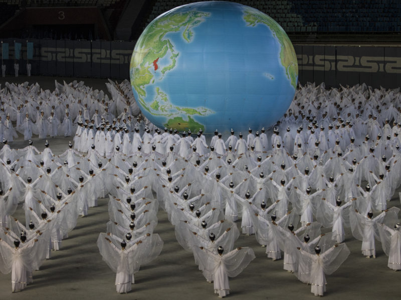 David Guttenfelder - North Korean women gather around a globe with a unified Korean Peninsula depicted on the map on the field of the May Day Stadium