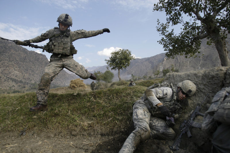 David Guttenfelder – Afghanistan - Cpl. Casey Liffrig, left, leaps for cover as Lt. Thomas Goodman gets down as insurgent fighters ambush US soldiers during a patrol in the Pech Valley of the Kunar province, Nov. 3, 2009. "A platoon of soldiers had gone to a nearby village to tell the elders to stop the insurgent from passing through to attack U.S. targets. The villagers said they just wanted to be left alone. They claimed they had asked the insurgent to stay away and wished the Americans would do the same. About 500 yards outside the town, the soldiers were ambushed and insurgent gunfire whistled down from the mountainside. Pinned down in an irrigation canal and a rice paddy with only small walls and terraces for cover, soldiers began bounding two-by-two across open fields to take cover. It took air support from helicopters and artillery, and the soldiers fighting back for four hours before they could retreat to safety. At one point in the battle, ammunition ran low. A helicopter hovered into a river bed and shoved out bullets and grenades on a medical stretcher for them to retrieve."