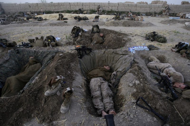 David Guttenfelder – Afghanistan - US Marines from the 2nd Marine Expeditionary Brigade sleep in their fighting holes inside a compound where they stayed for the night, in the Nawa district of the Helmand province, July 8, 2009. "In July, the US Marines launched a 4,400-Marine air assault into Afghanistan’s Helmand province. It was part of what we were all calling ‘Obama’s Surge,’ the first troops who would have the new president’s signature at the bottom of their deployment papers. The unit I was attached to was sent to the northern part of the province to an area where NATO troops had never gone. "Most soldiers and Marines, when they come to Afghanistan, are sent to a pre-existing combat outpost, so they already have a base to return to most every night. But these guys literally stepped off a helicopter in the middle of the night, in a hostile area, and started walking and looking for a home. It was more than 120 degrees. We walked as far as 10 miles a day for well over a week and carried all of our gear, food and water on our backs. And every night, we made camp wherever we could. On the sixth night of the operation, we made camp inside a large mud-walled farmers' field. Everyone dropped their heavy packs. The area was very open and vulnerable to mortar attacks, so the guys were told to begin digging in the dark to make firing positions where each man would sleep for the night. I had to borrow a small collapsible spade from one of the Marines to dig my own grave-sized bed. It was too dark to make photos that night, and I was busy digging my own hole. I woke before dawn so I could make this photograph of the guys while most were still sleeping. The Marines paid rent to the farmer and damages to the field."
