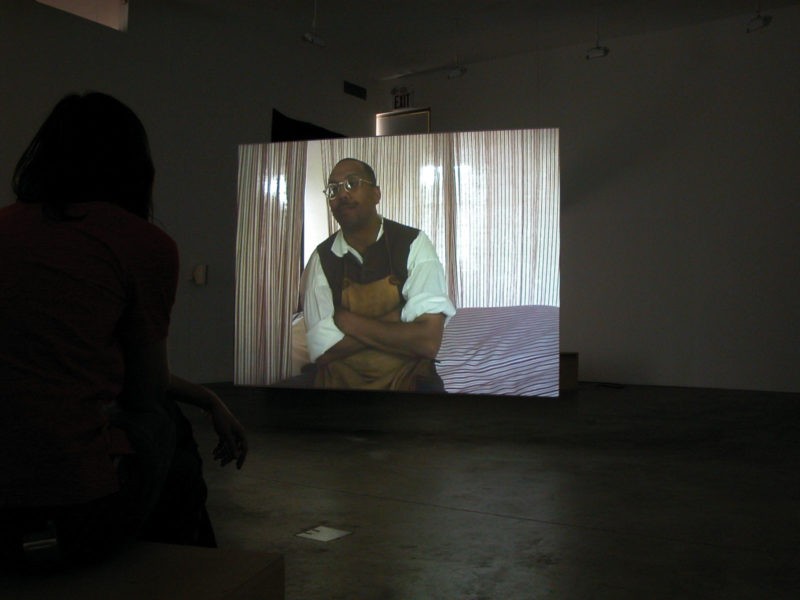 Omer Fast - Godville, 2005, Two channel video installation, 50 minutes, Installation view, Postmasters Gallery, New York