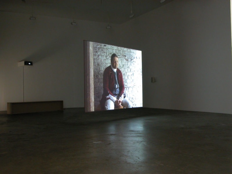 Omer Fast - Godville, 2005, Two channel video installation, 50 minutes, Installation view, Postmasters Gallery, New York