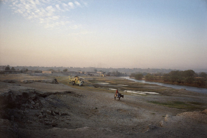 Stephen Dupont – The destroyed idyll; soft light, green slopes, a quiet river, a woman on a donkey, a combat helicopter, Yangi Qala, North Afghanistan, 1998