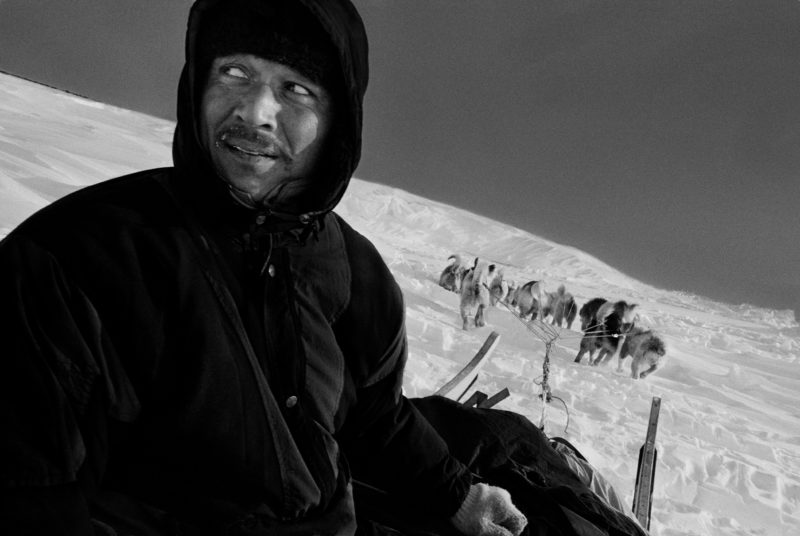 Ragnar Axelsson - Last Days of the Arctic - Hunter Hjelmer Heimeken riding his dog sled on the way home from a hunting trip on the east coast of Greenland