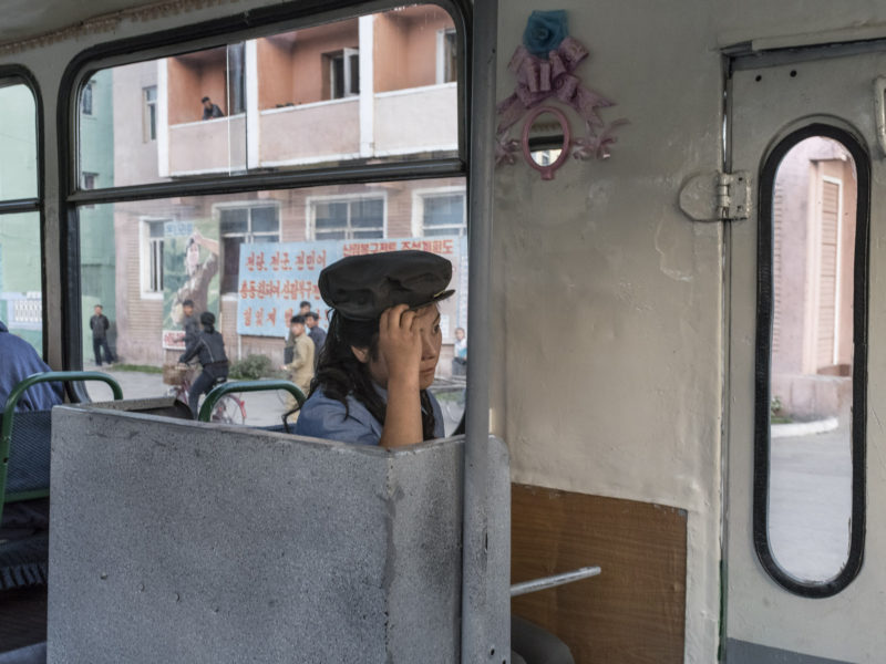 Carl De Keyzer - Chongjin, North Hamgyong Province. A trolley-bus attendant. While the number of cars, including taxis, has increased in recent years, city dwellers make extensive use of public transportation. 20 September 2015 5:00 PM