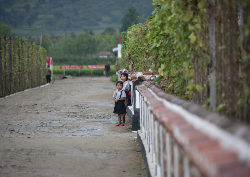 Eric Lafforgue – North Korea - Two little girls standing on a road near a farm in Hamhung